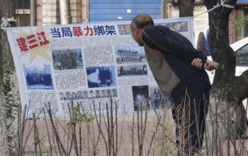 A Chinese citizen in Jiamusi, Heilongjiang Province, reads a banner hung by Falun Gong practitioners in 2018 that reads “Kidnapped by Authorities” detailing persecution cases in the area (Credit: Minghui.org)